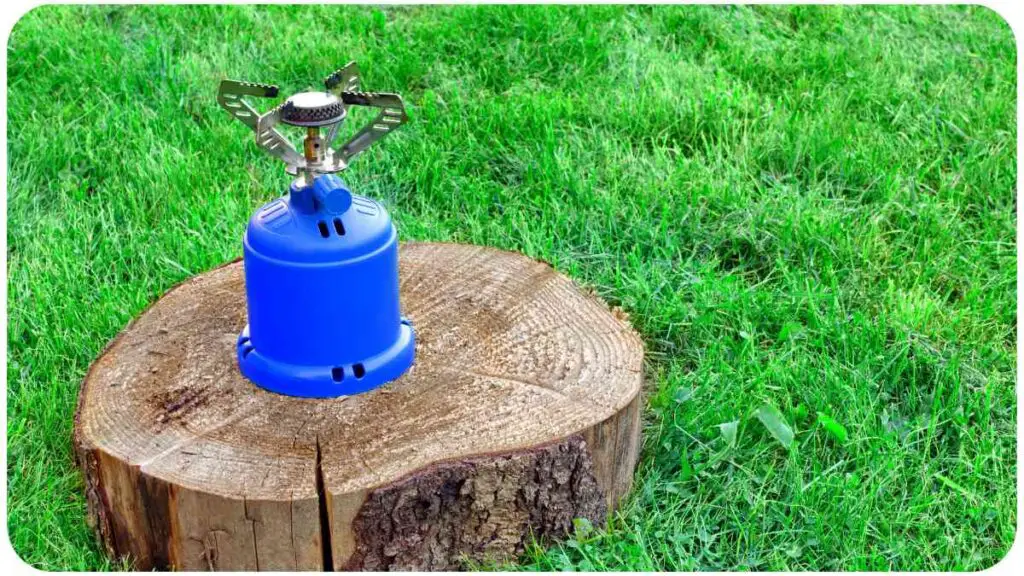 a blue camping stove sitting on top of a tree stump