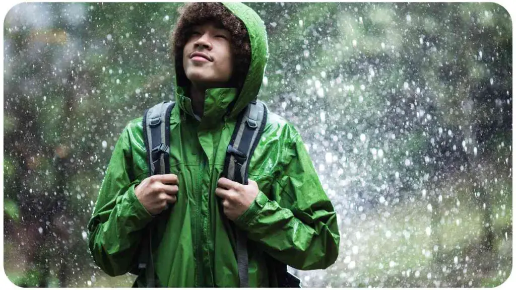 a person in a green rain jacket standing in the rain